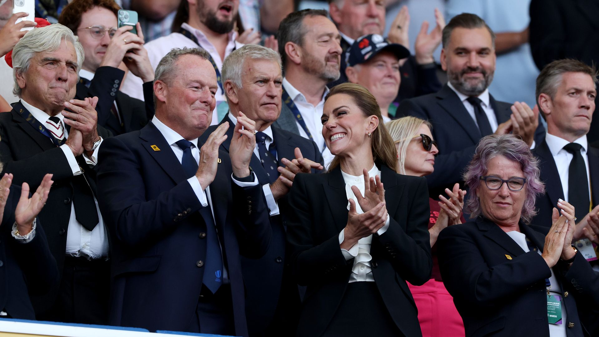 Kate Middleton smiling and applauding while in a crowd