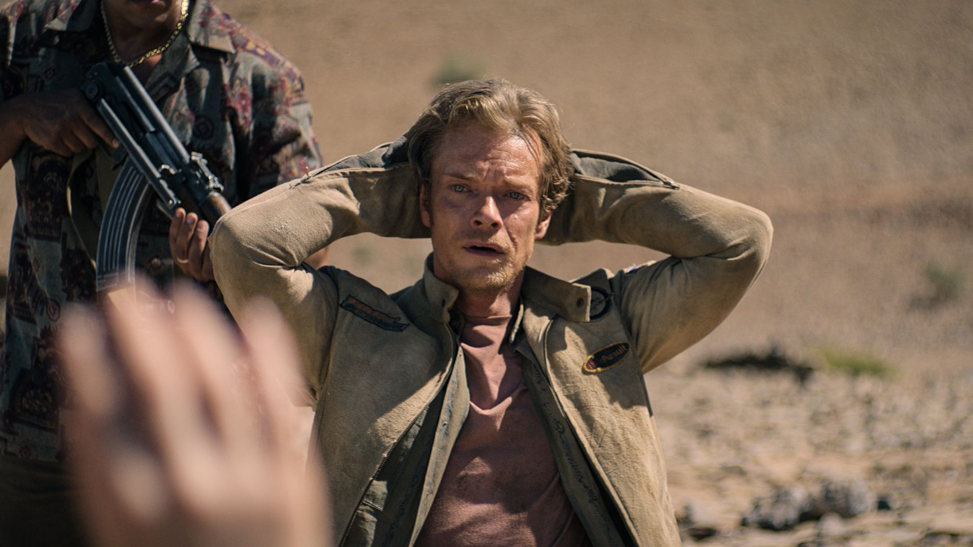 Man sits with hands behind his head