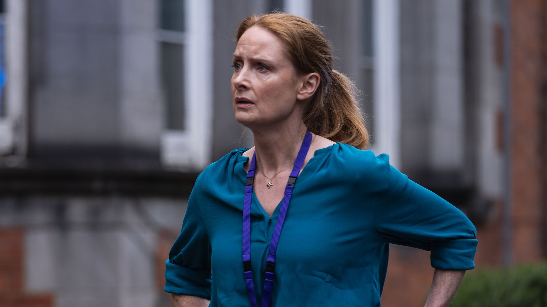 woman with red hair in blue shirt outside building