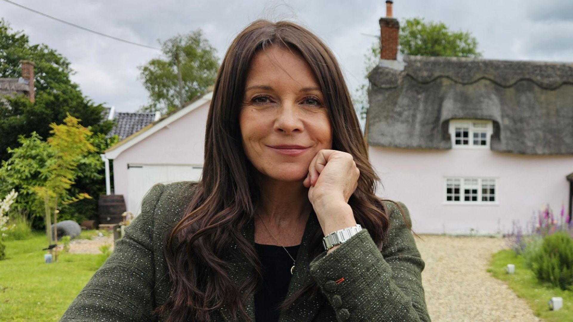 woman leaning on white fence outside thatched house