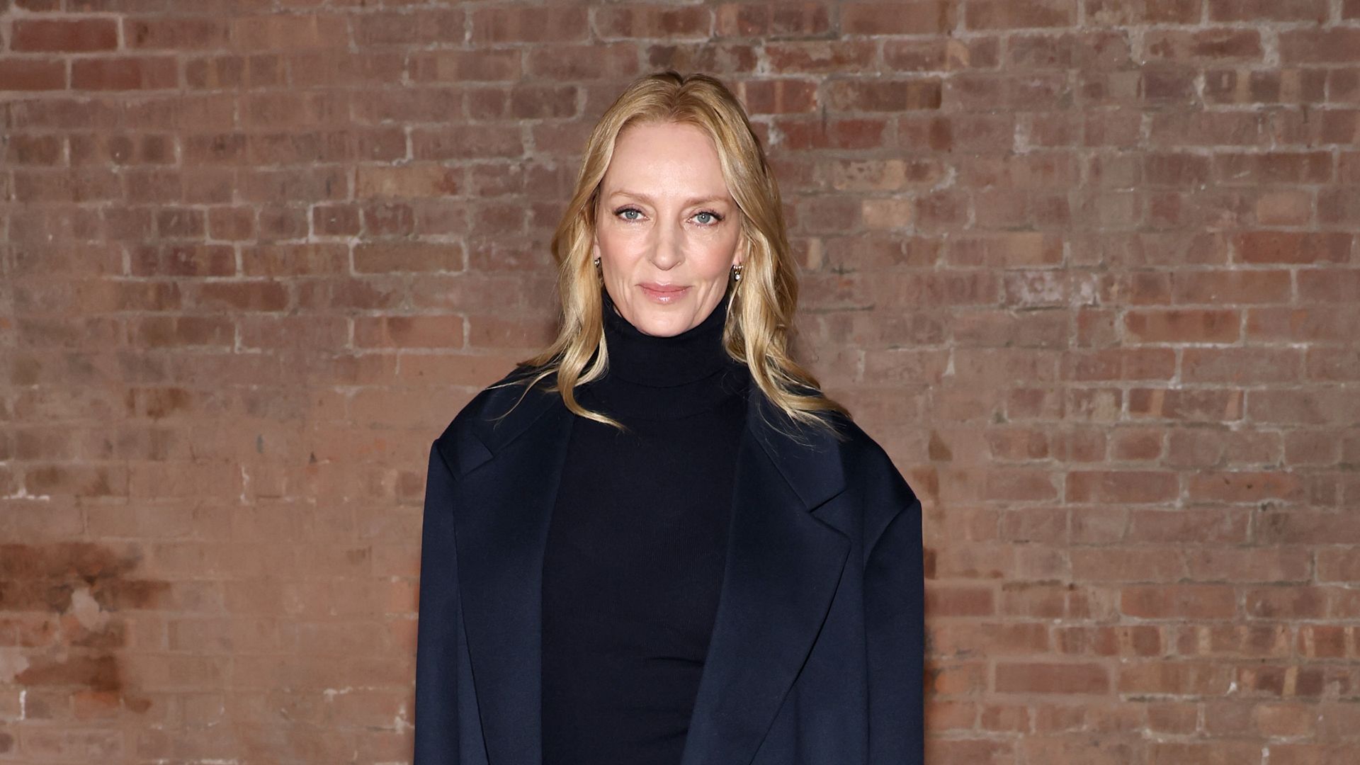 Uma Thurman in brown trousers and navy jumper and coat