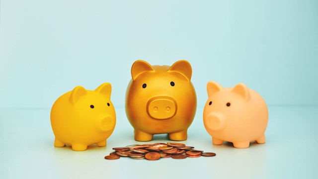 Three piggy banks standing around a pile of cash. Savings and investment theme