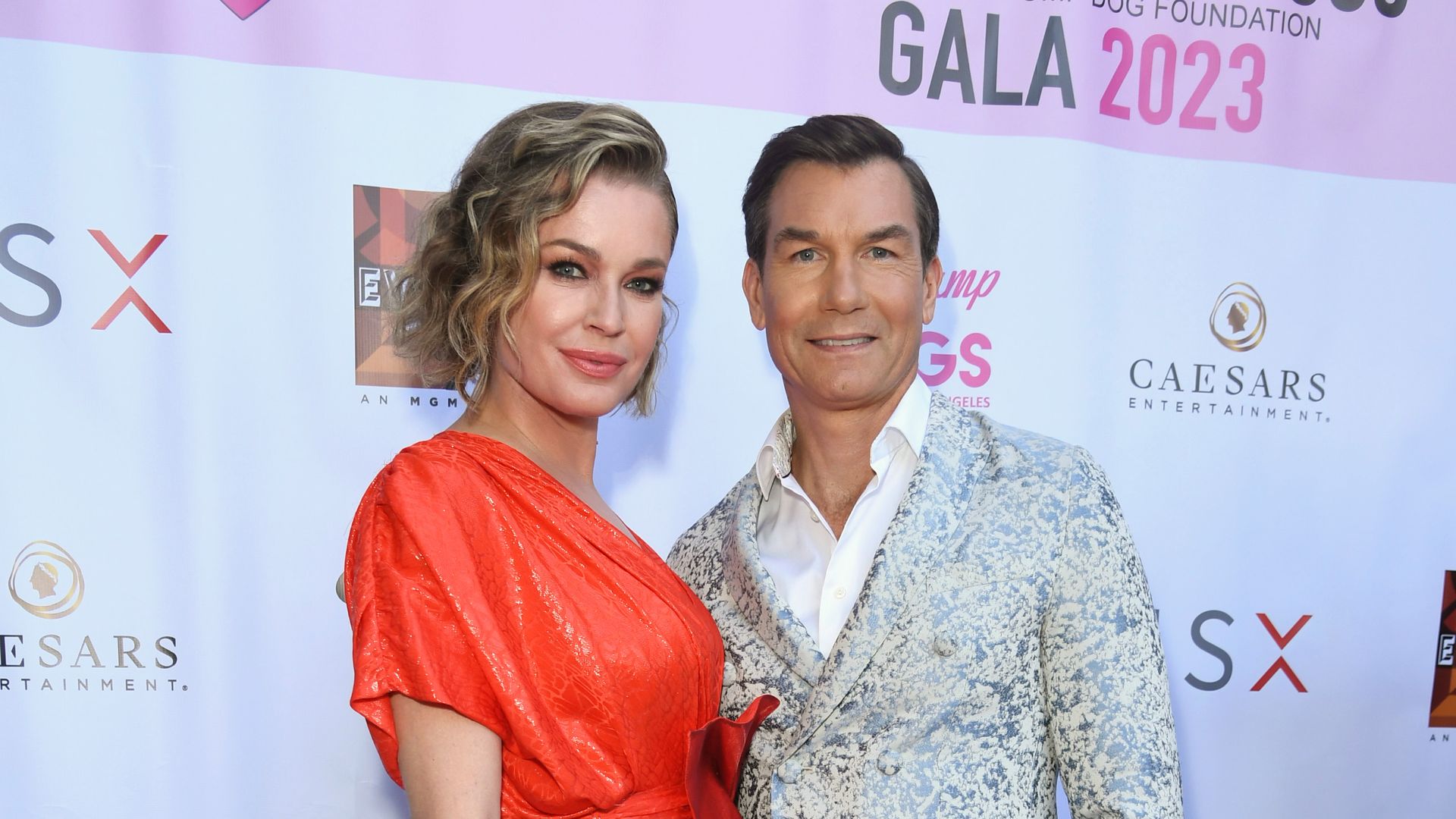 rebecca romijn in orange dress and jerry o'connell in grey suit