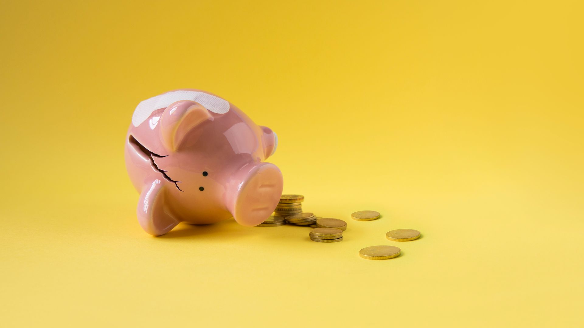 Broken fallen piggy bank with coins scattered around