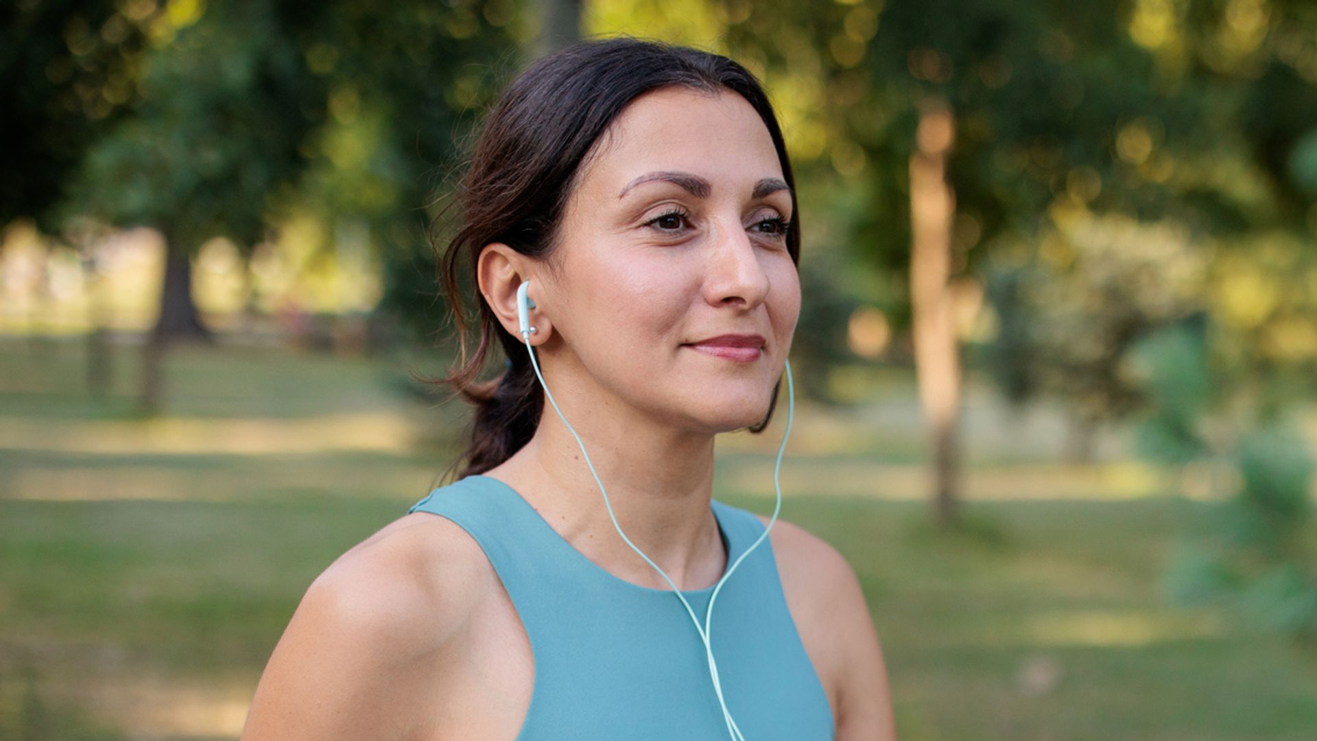 A mid adult woman listening to music while walking in a public park