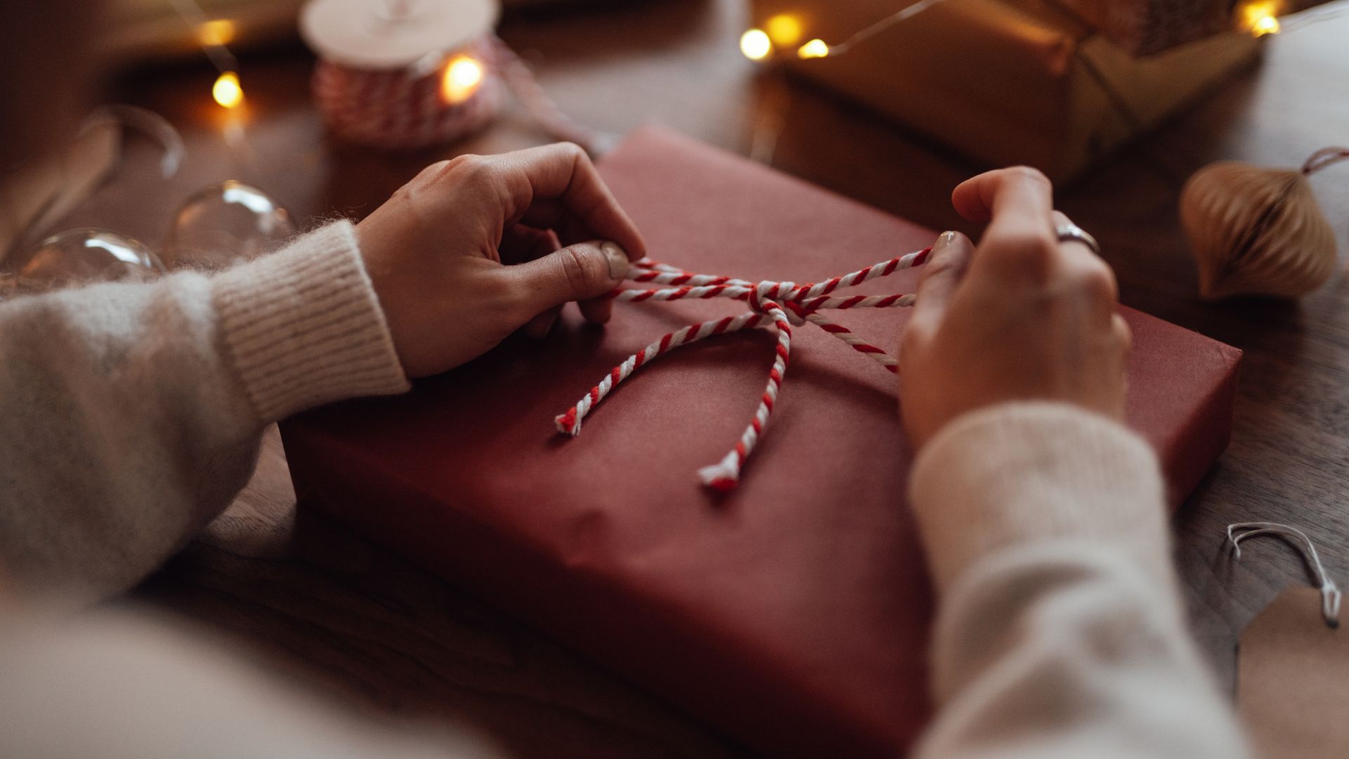 Close-up of female hand tying a bow on Christmas gift. Christmas sale. Christmas preparation.