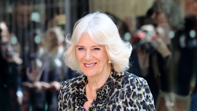 queen camilla smiling in a leopard print dress