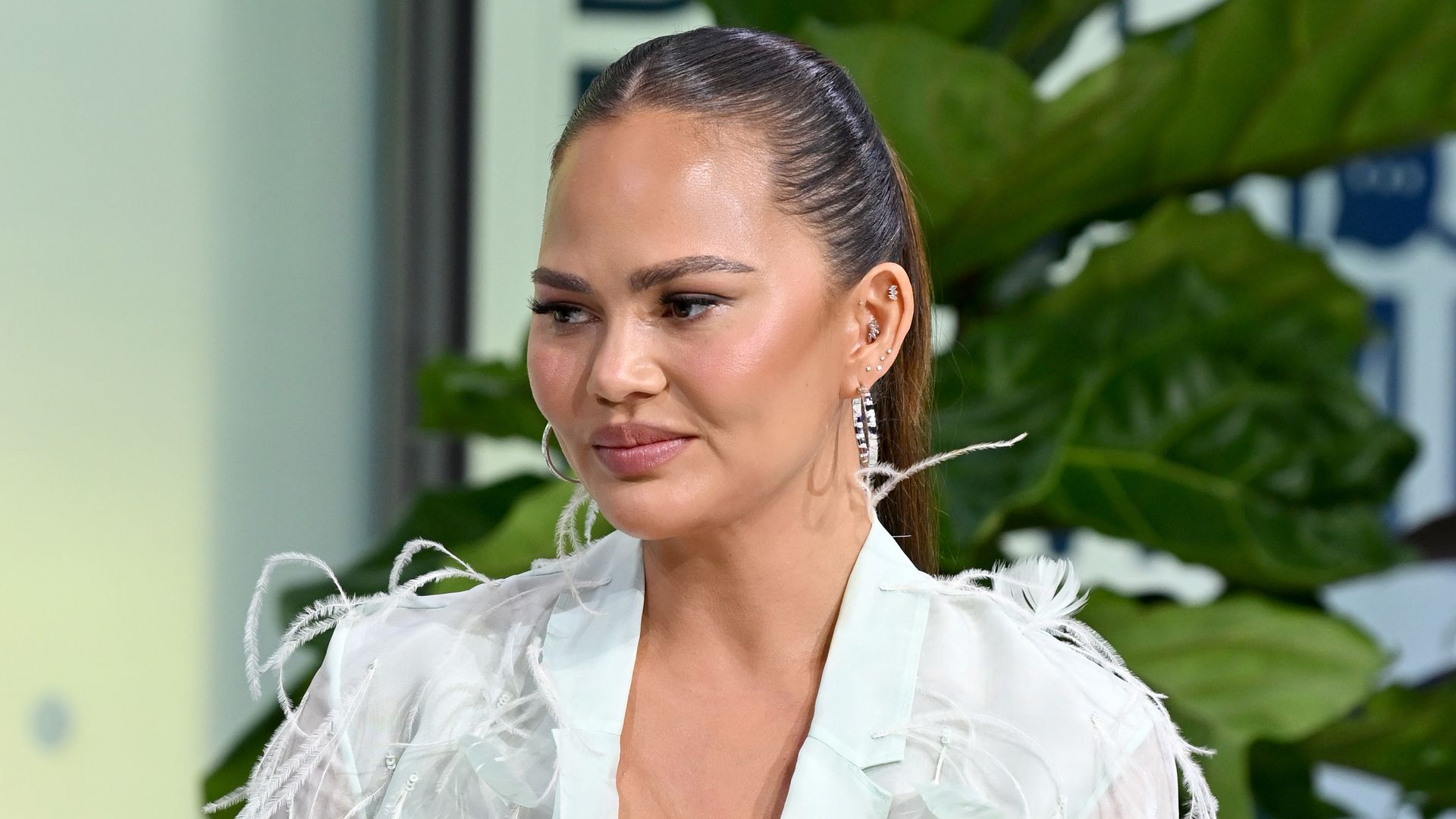 Chrissy Teigen looks like a swan in feathered mini dress as she ...