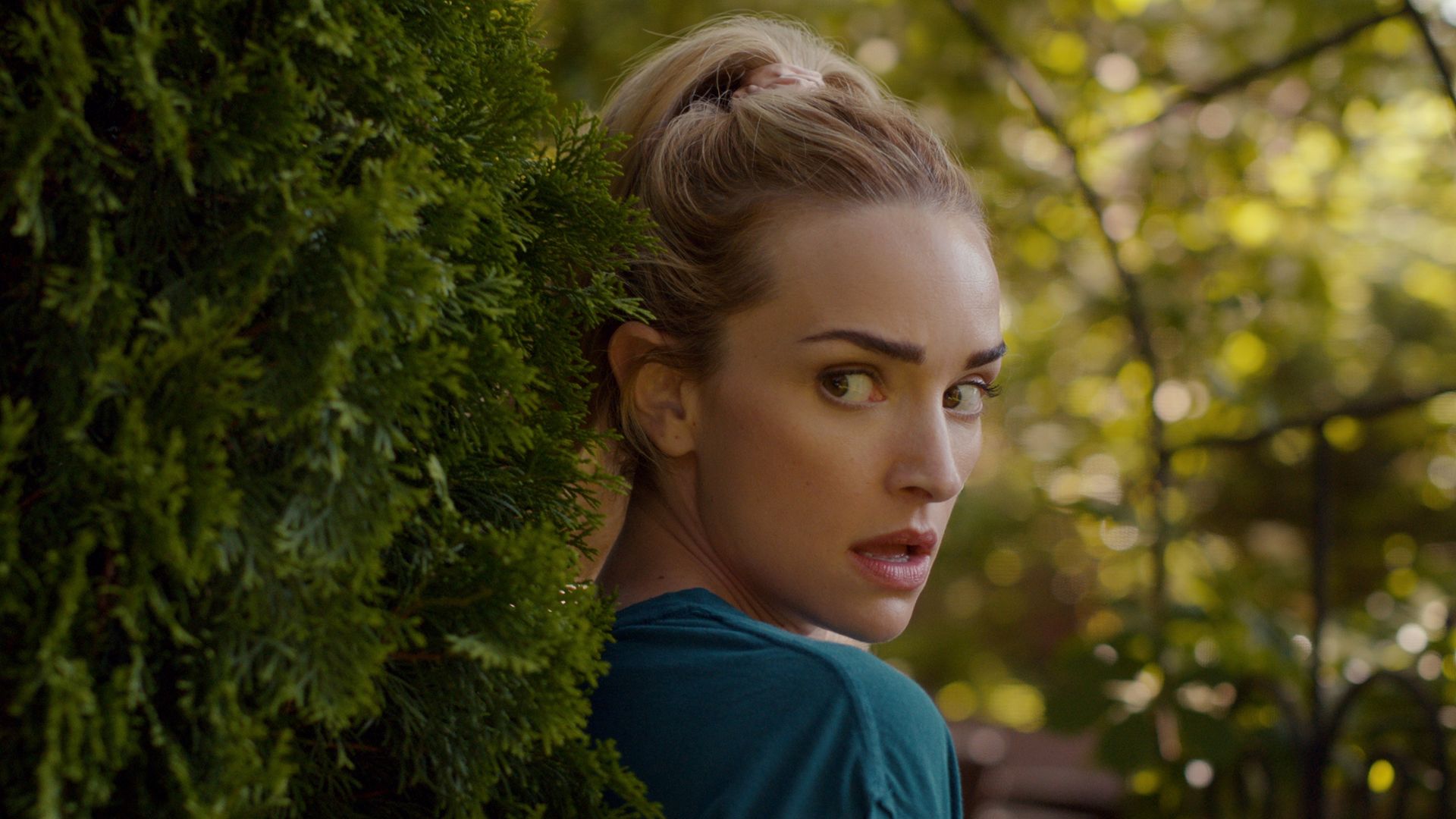 blonde woman hiding behind bush