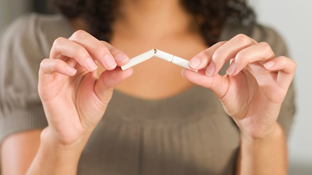 Mixed Race woman breaking cigarette