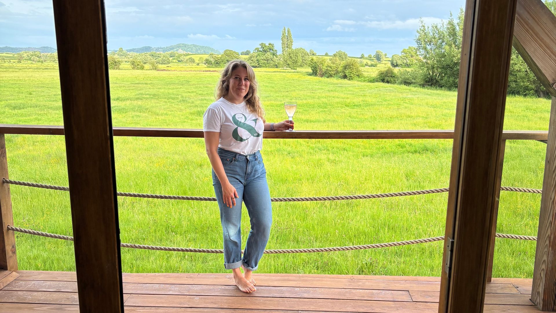 woman standing with a glass of wine on a wood balcony