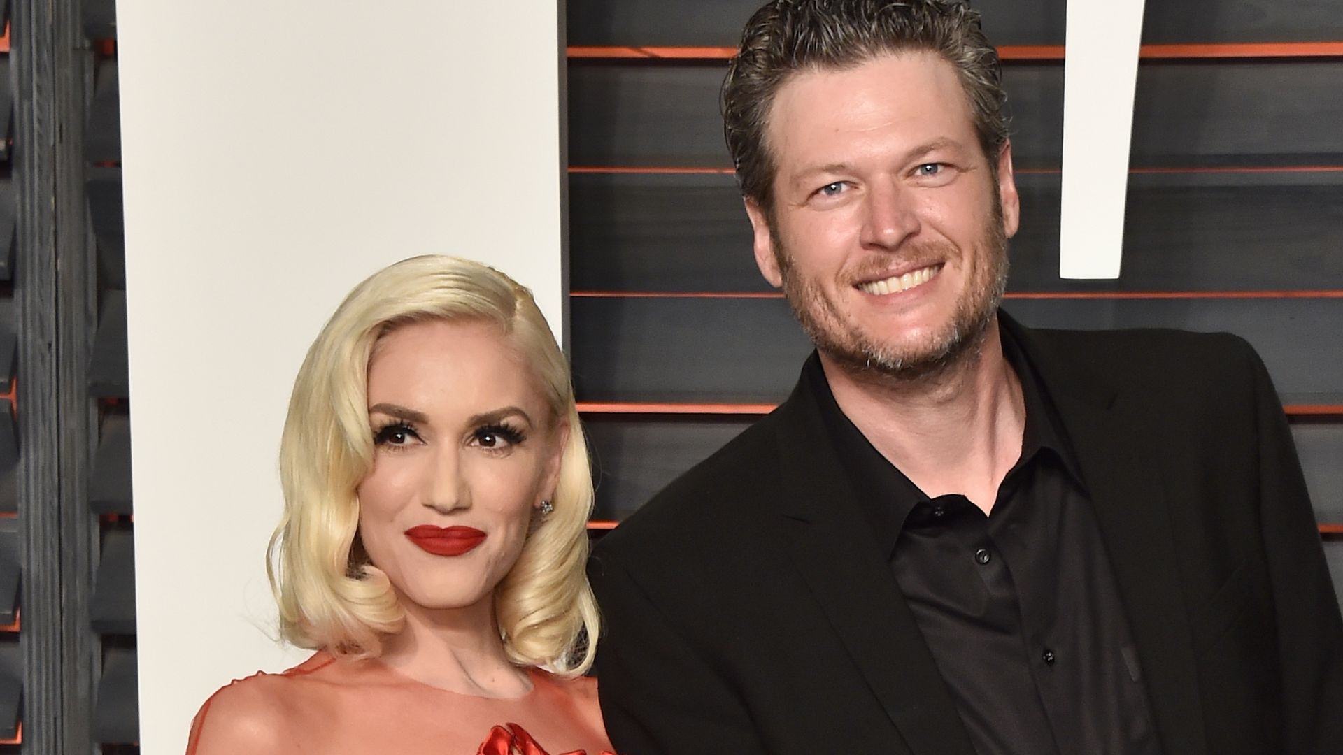 Gwen Stefani in a red dress with Blake Shelton in a black suit