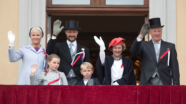 Crown Princess Mette-Marit, Crown Prince Haakon, Princess Ingrid, Prince Sverre, Queen Sonja and King Harald waving from a balcony