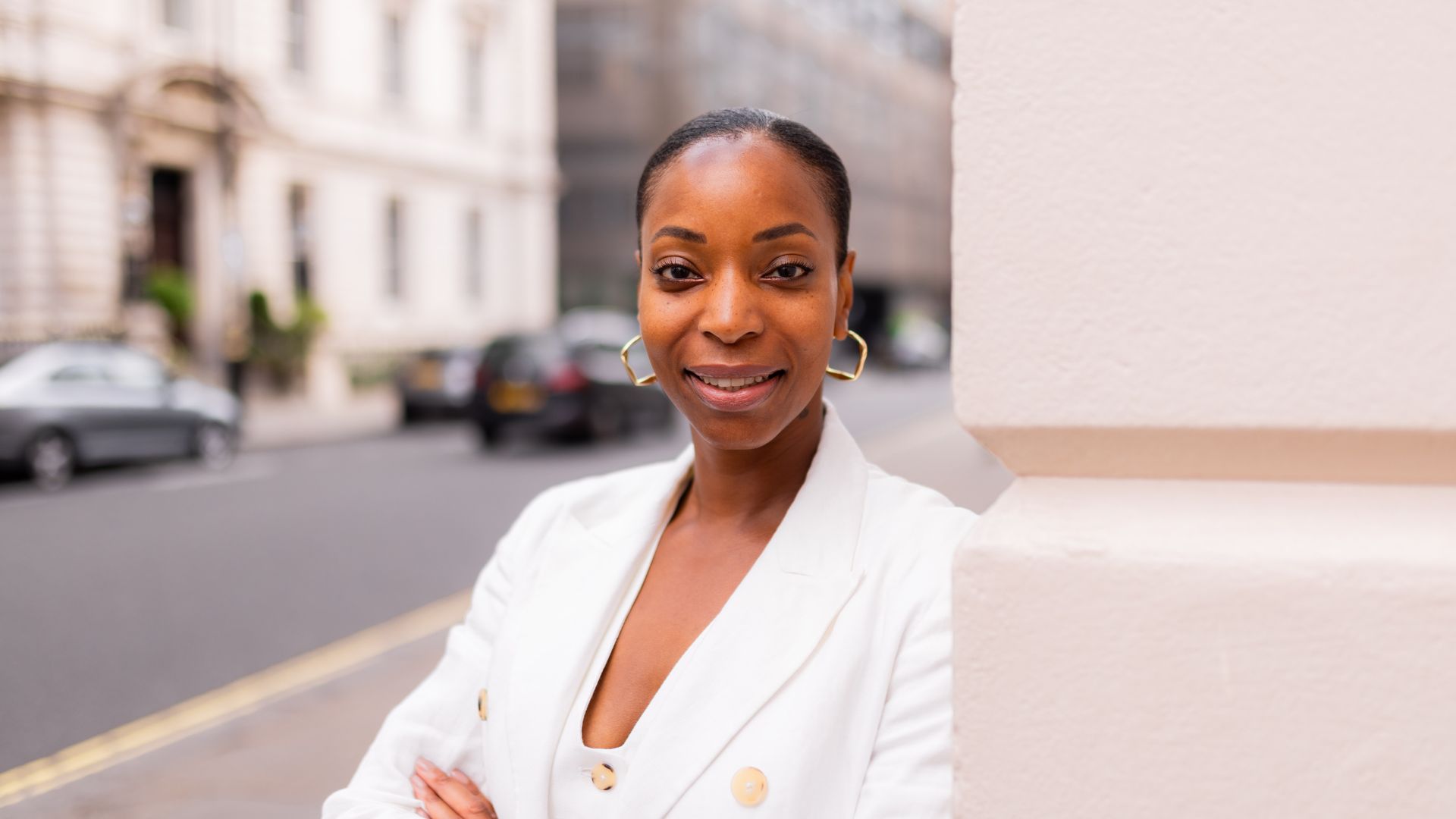 woman smiling  in a smart white suit with gold buttons 