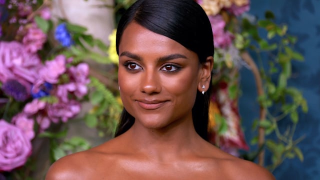 Simone Ashley in a strapless dress against the backdrop of flowers