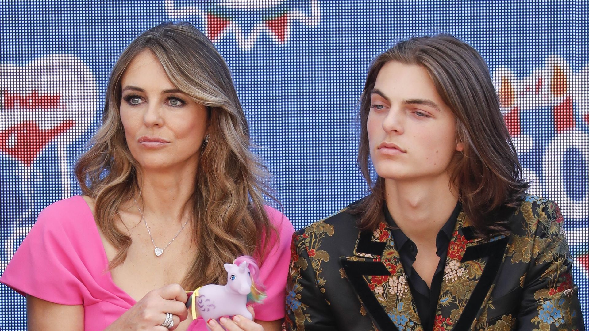 Elizabeth Hurley in pink dress with Damian Hurley, both expressionless