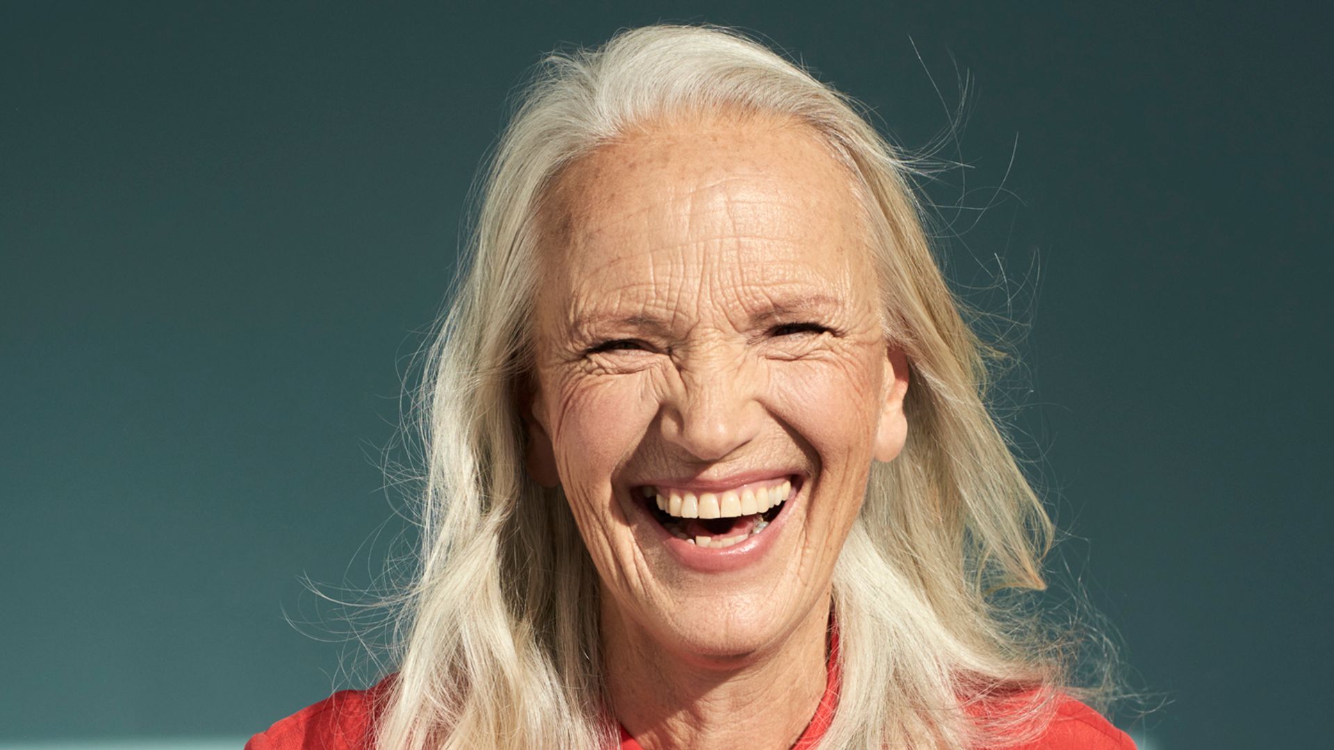 woman in sixties laughing in red shirt