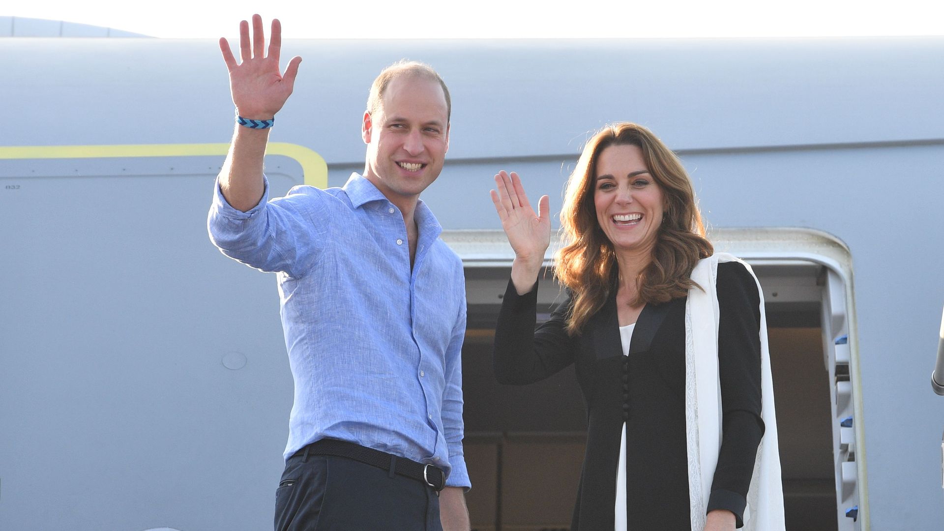 Prince William and Kate Middleton waving before entering an aeroplane