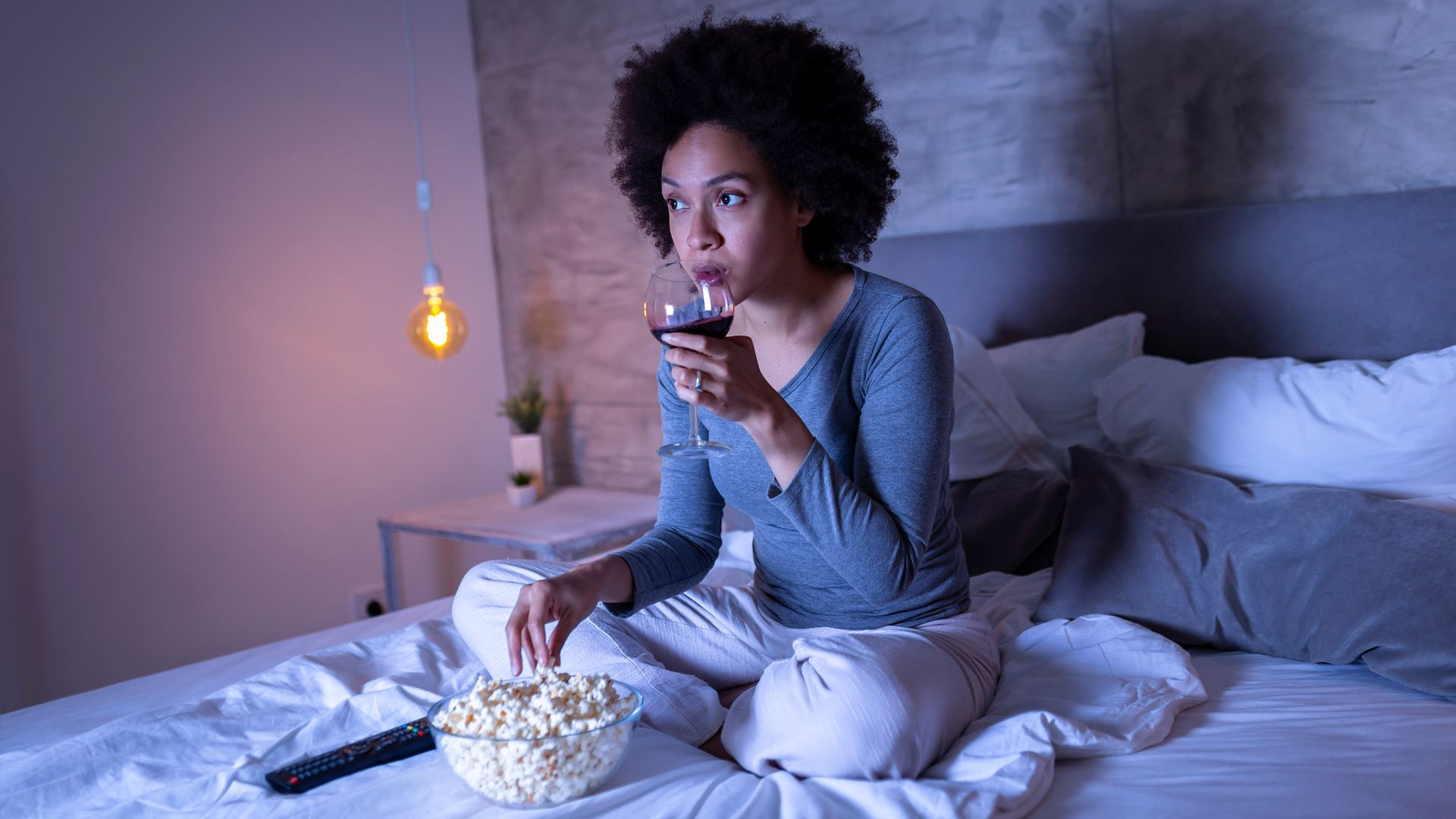 woman eating popcorn drinking wine at home