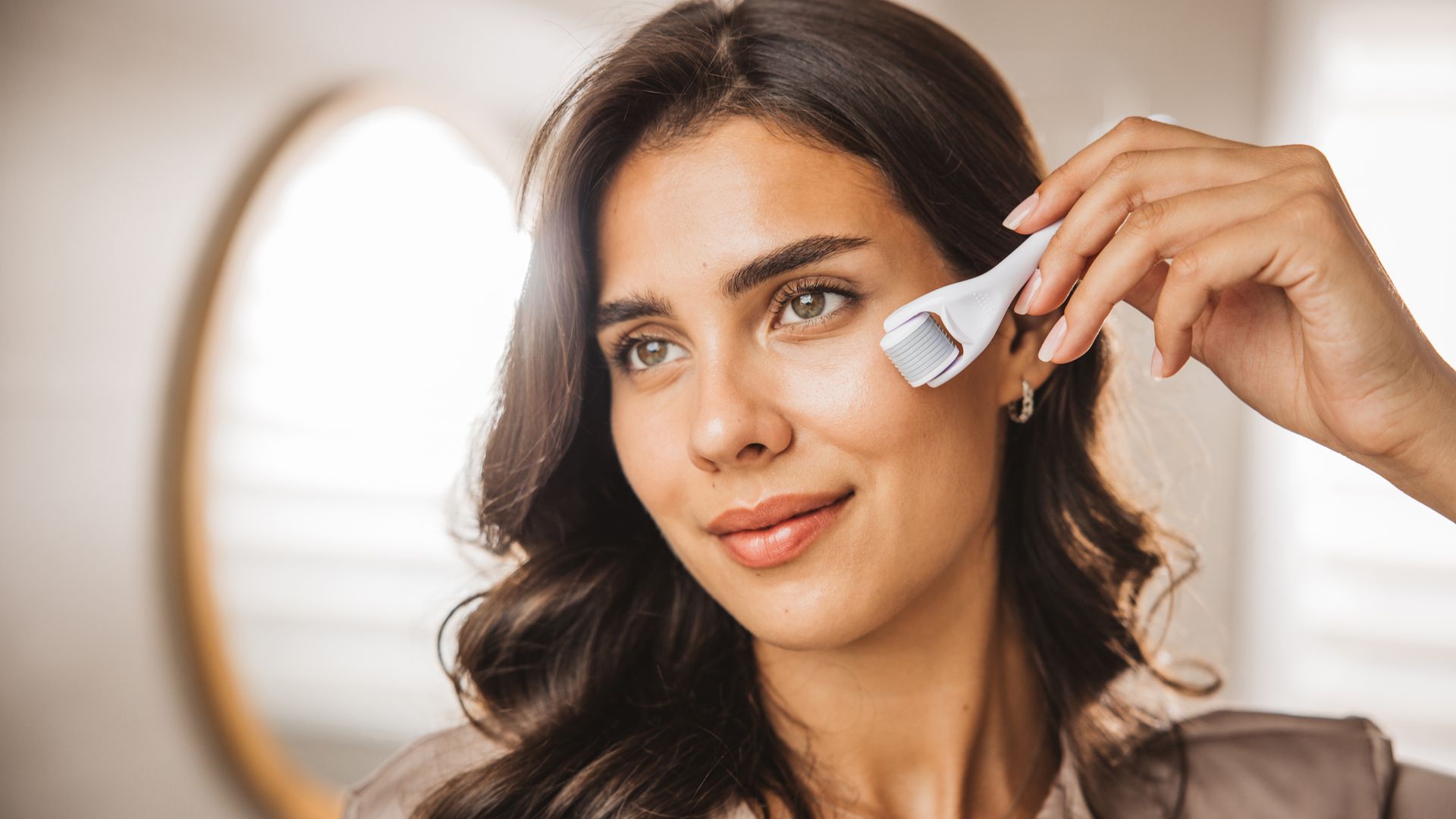Young woman looking in mirror and using micro needle meso derma Roller.