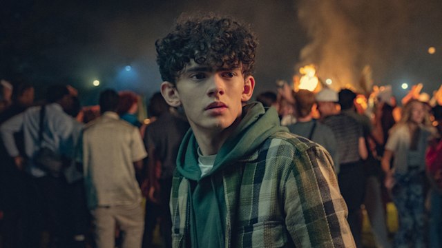 teenage boy standing in front of crowd of people