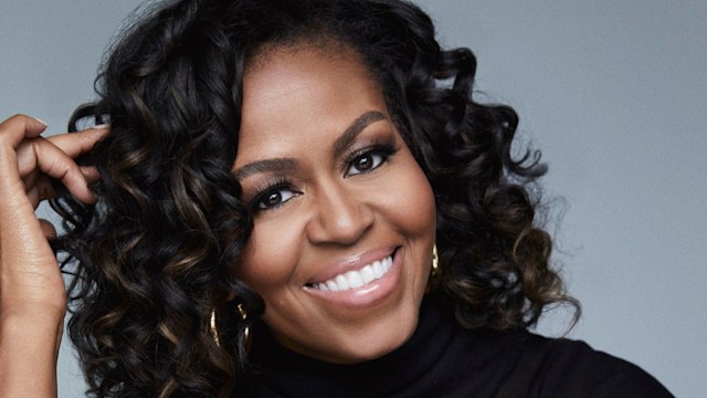 Michelle Obama in a black polo neck top smiling