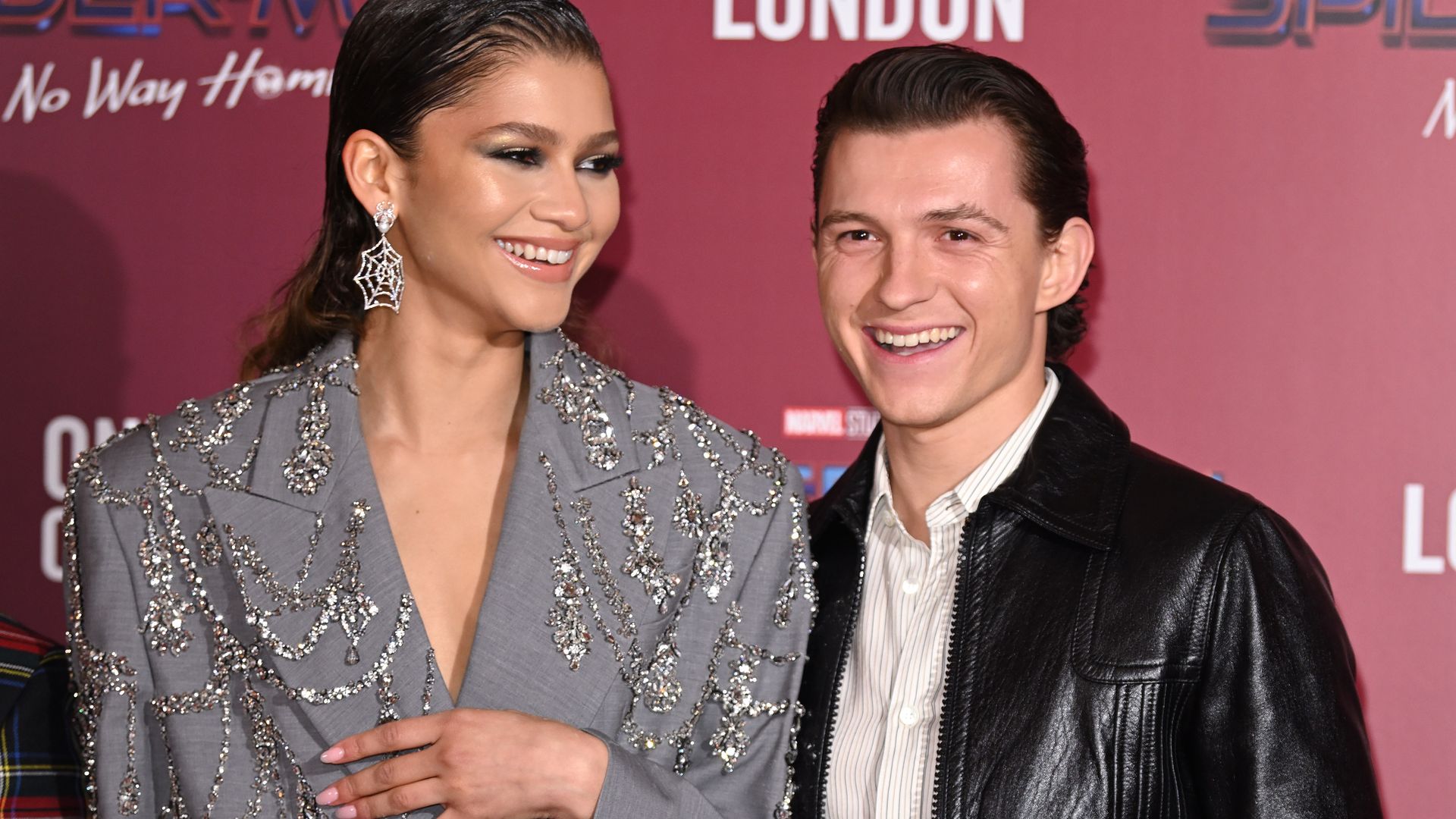 Tom Holland and Zendaya smiling on a red carpet
