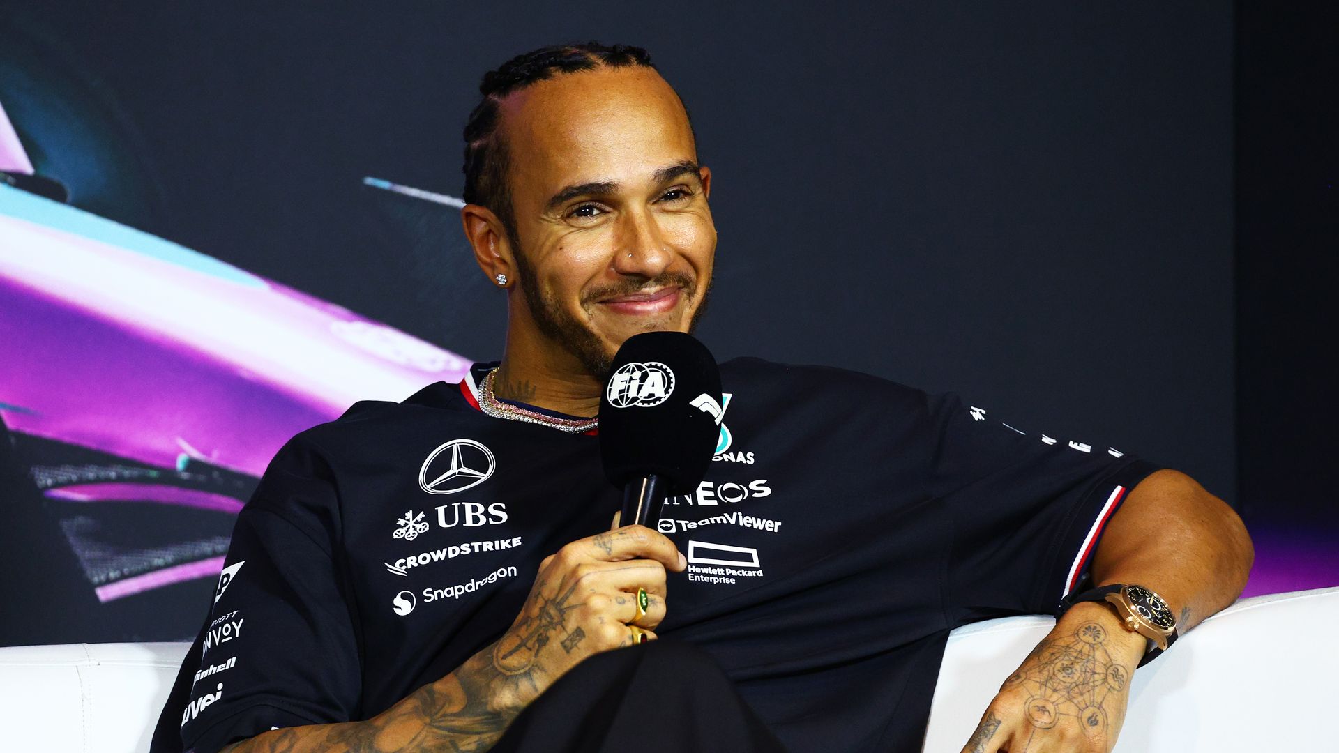 Lewis Hamilton holding a microphone in a black shirt