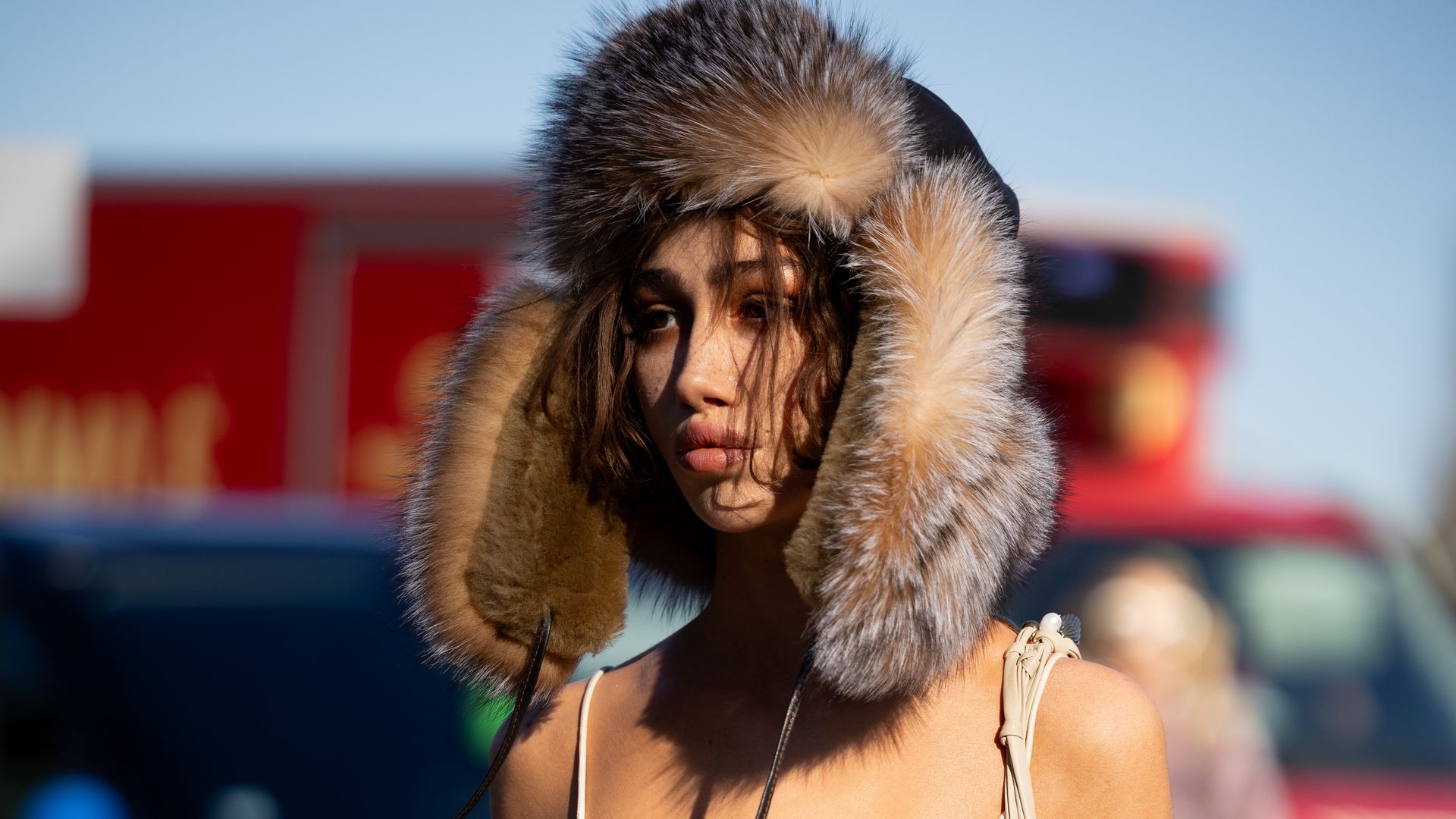 A guest wears a black and beige fur hat, white lace trousers and a beige leather bag and a white lace bra outside ChloÃ© show during the Womenswear Fall/Winter 2025/2026