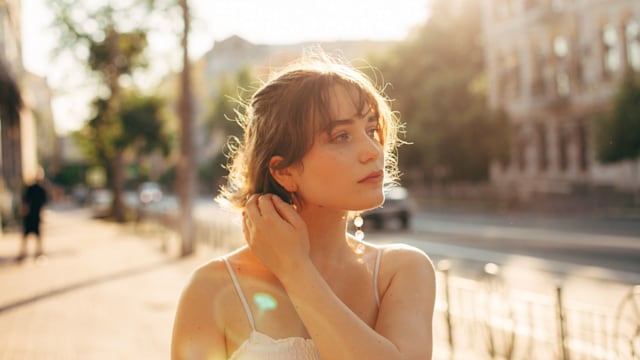 Beautiful young woman walking on the city street during summer