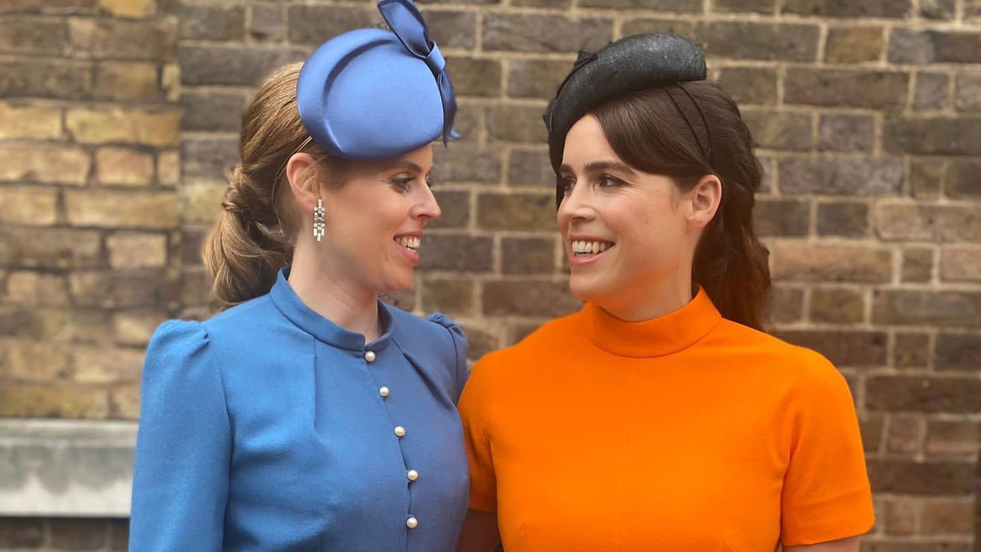 Princess Beatrice wearing blue dress and Princess Eugenie wearing orange dress