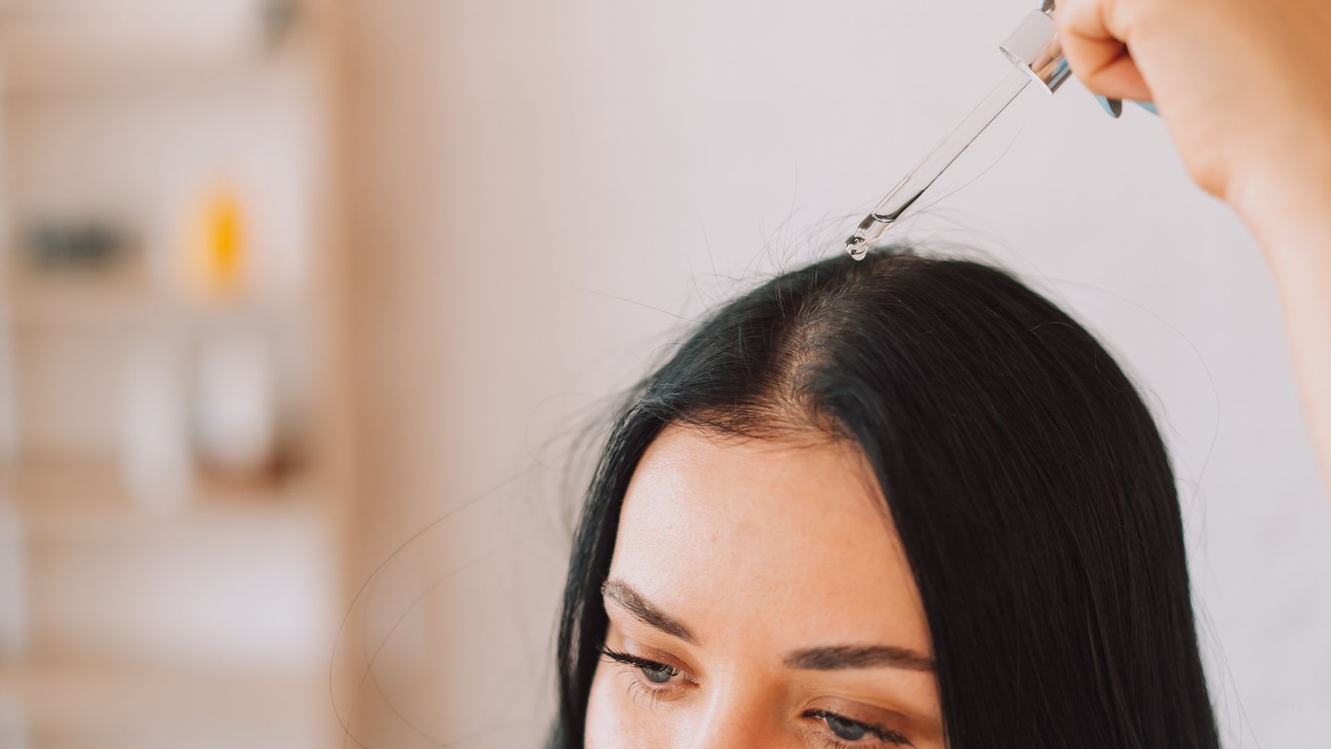 Lady applying serum on scalp and hair from pipette.