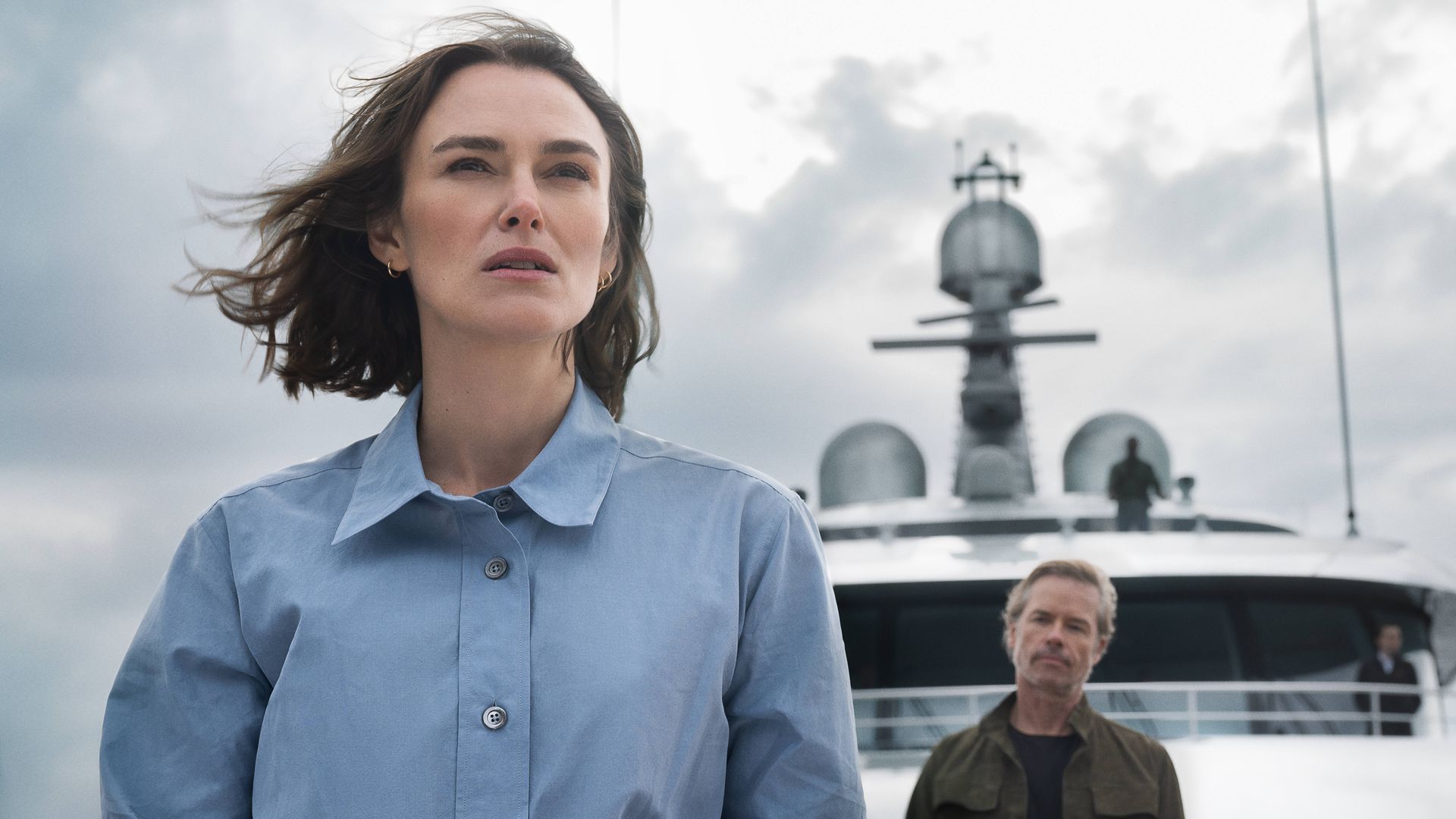 woman standing on boat, two men behind her