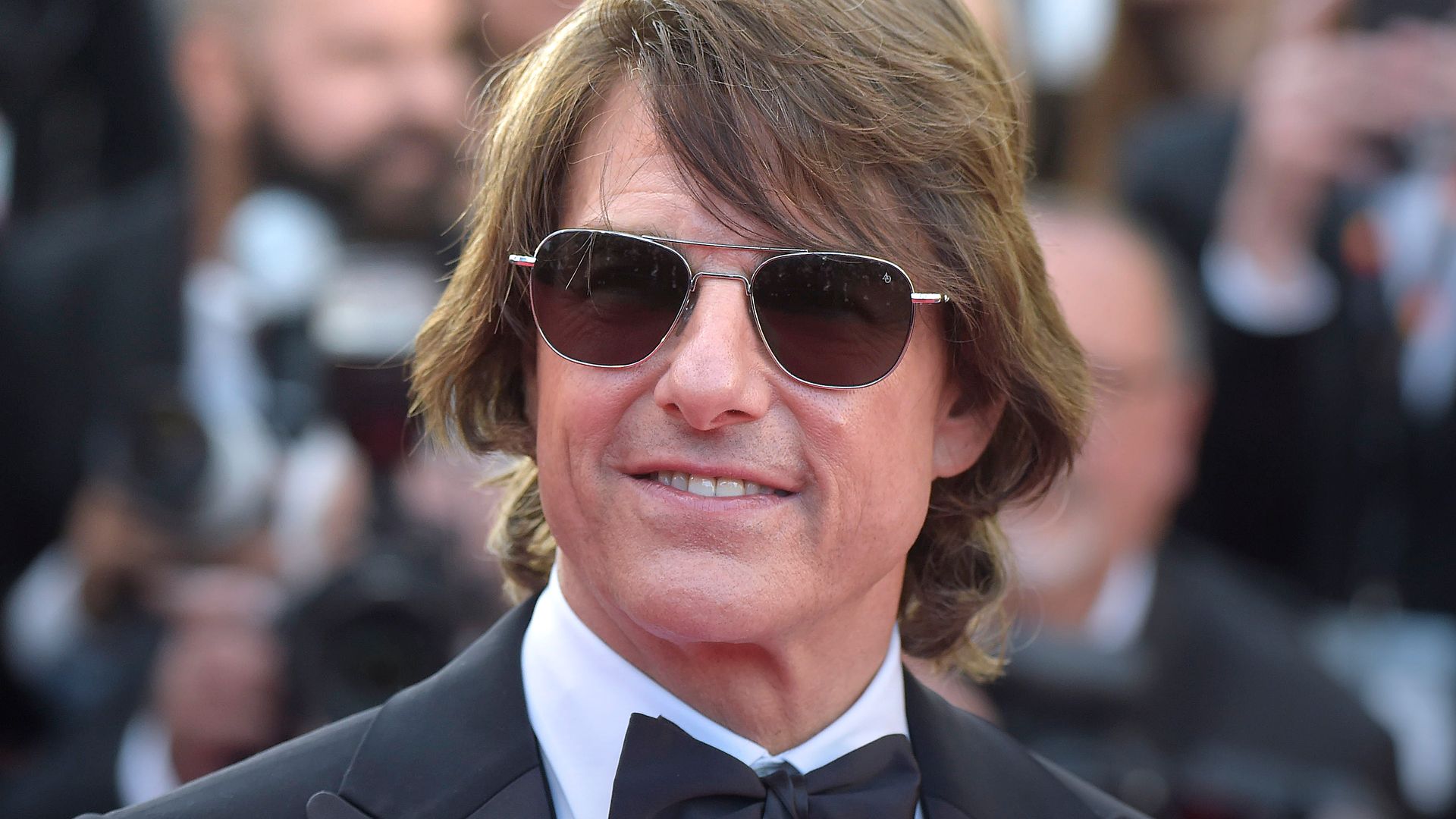 A photo of a brunette man in a suit and bow-tie