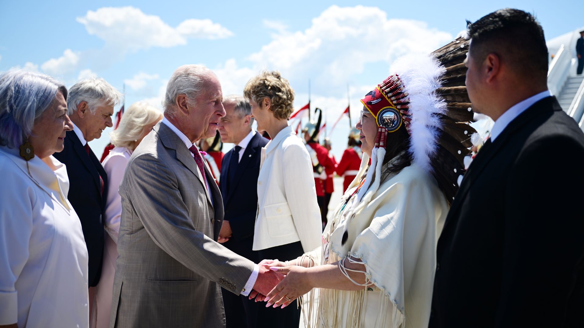 King Charles shaking hands with a woman in tribal dress