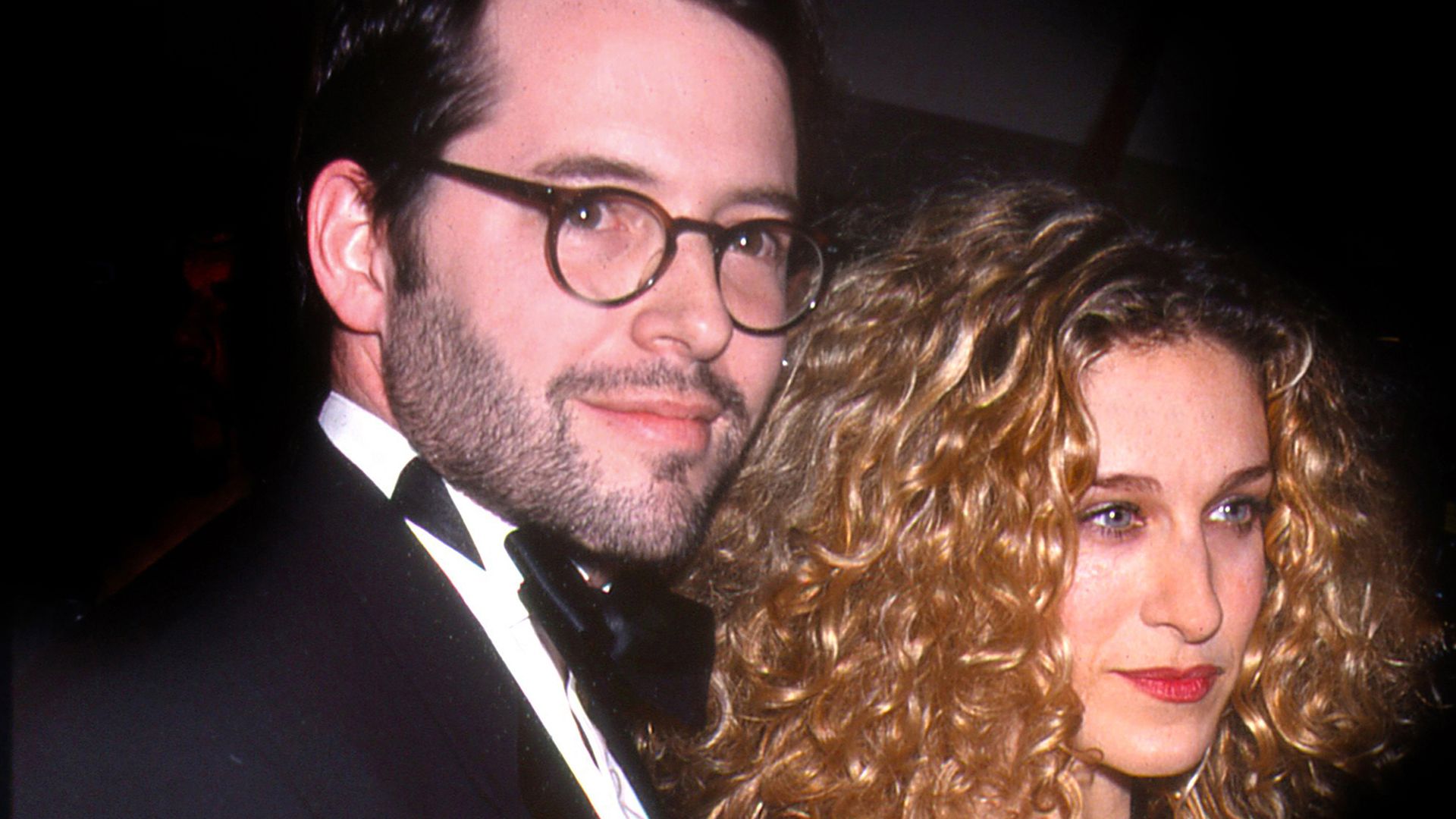 Matthew Broderick in a suit and bow tie and Sarah Jessica Parker in a black sparkly dress and red lipstick