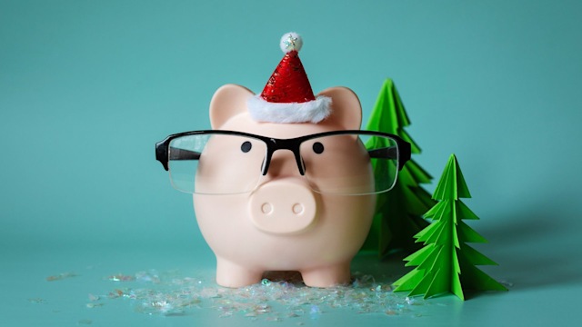 Piggy bank with glasses and a santa hat next to trees