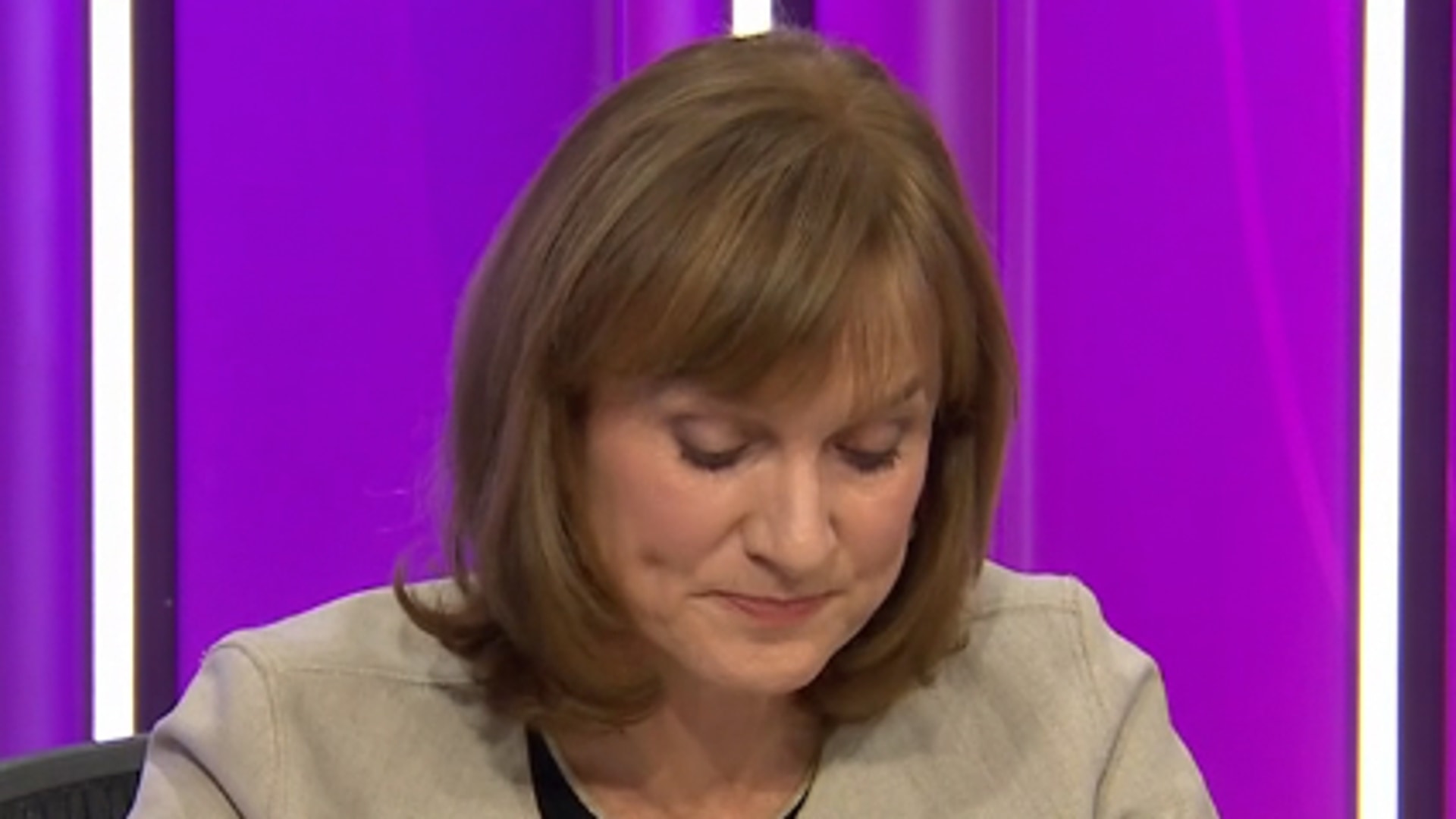 Female TV host looking down at desk in studio 