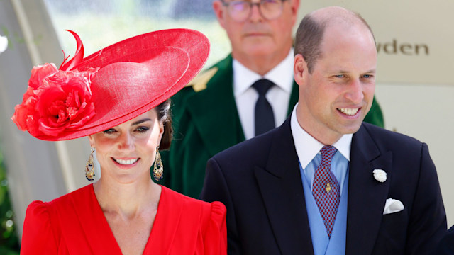 Kate Middleton in a red outfit and Prince William in a black suit