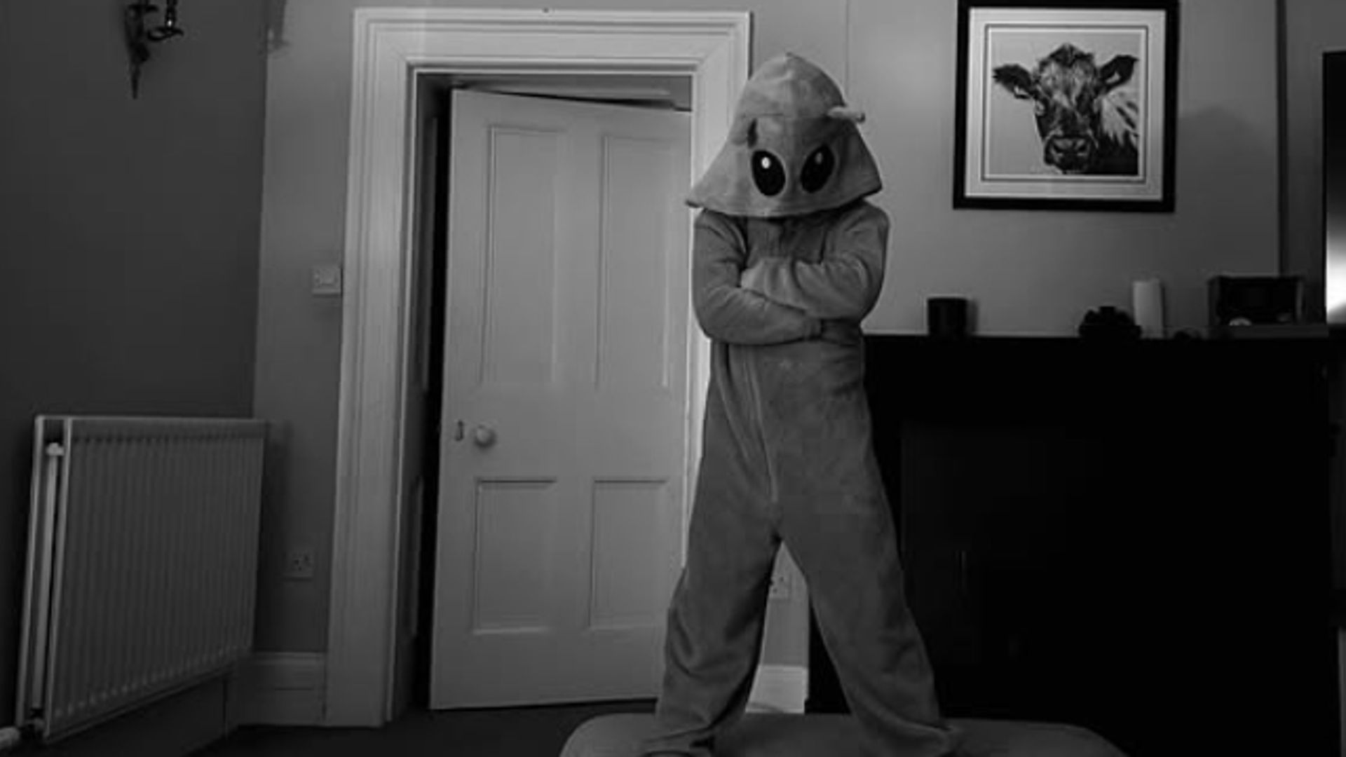 A young boy in an alien onesie standing in a lounge