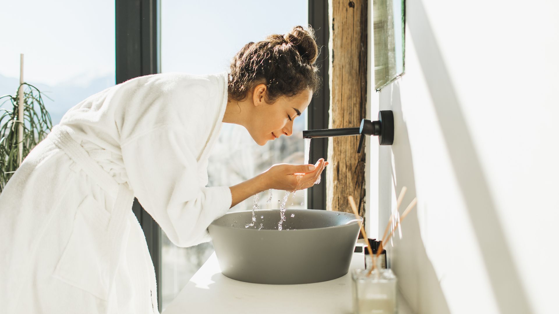 woman awakening, washing and cleaning her face with splashing water