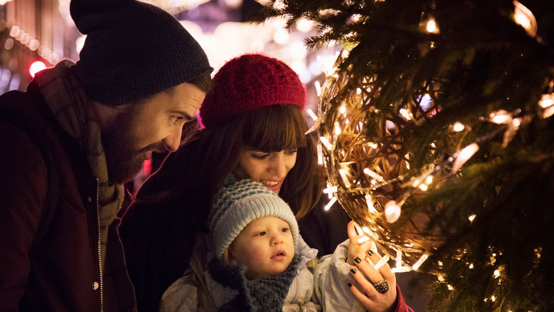 Parents show their child the christmas lights on christmas tree in city centre