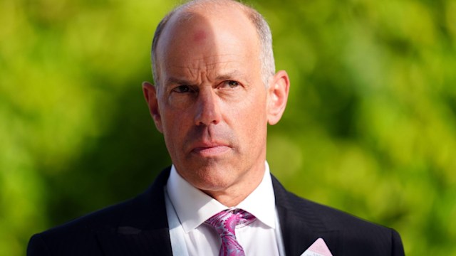 Phil Spencer looking serious in black suit with pink tie and pocket square 