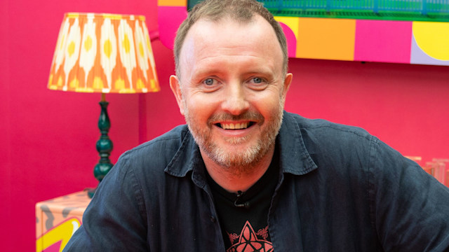 Chris McCausland in a pink room with yellow furniture