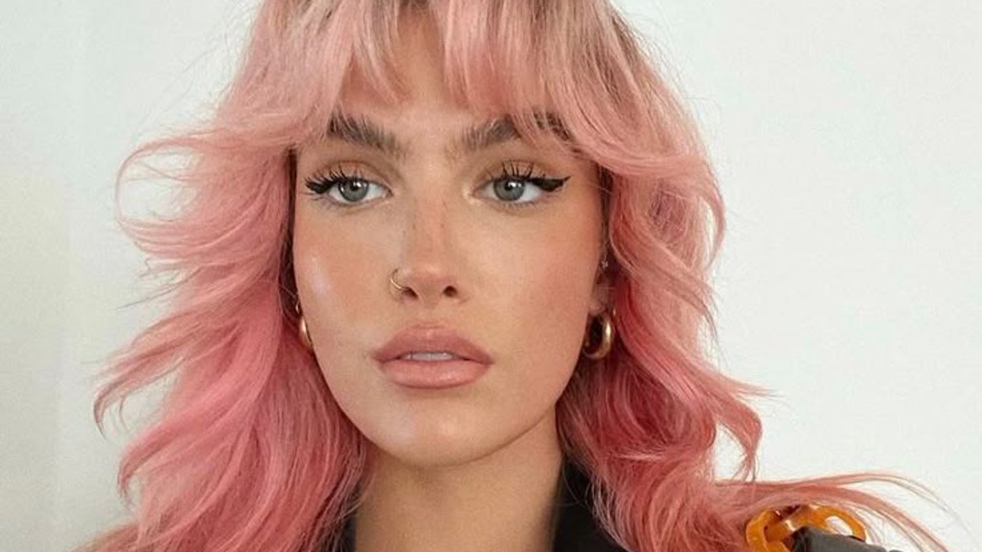 girl with pastel pink hair with bangs and layers 