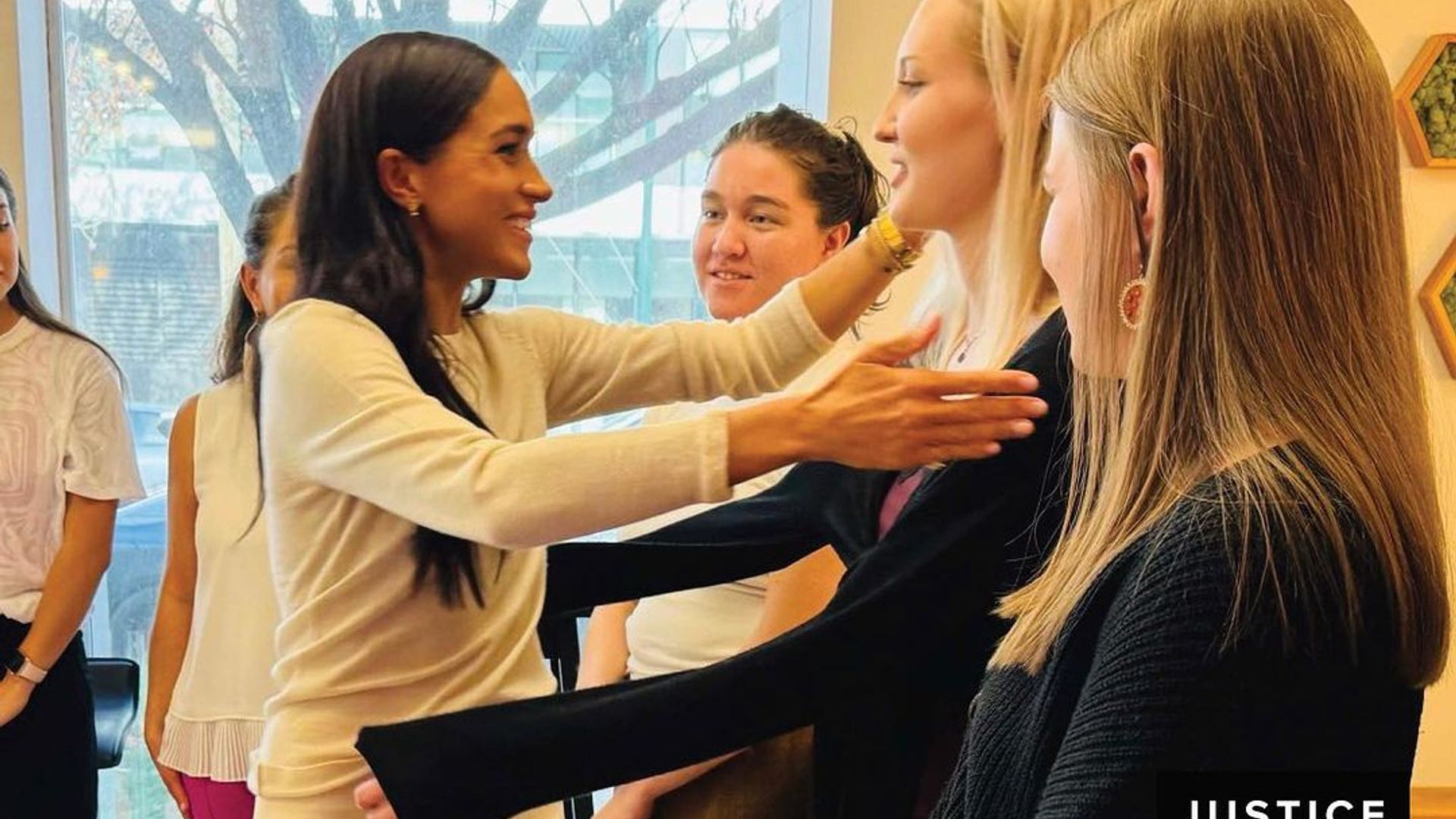 Meghan reaches out to hug the girls at her recent visit to Justice for Girls charity