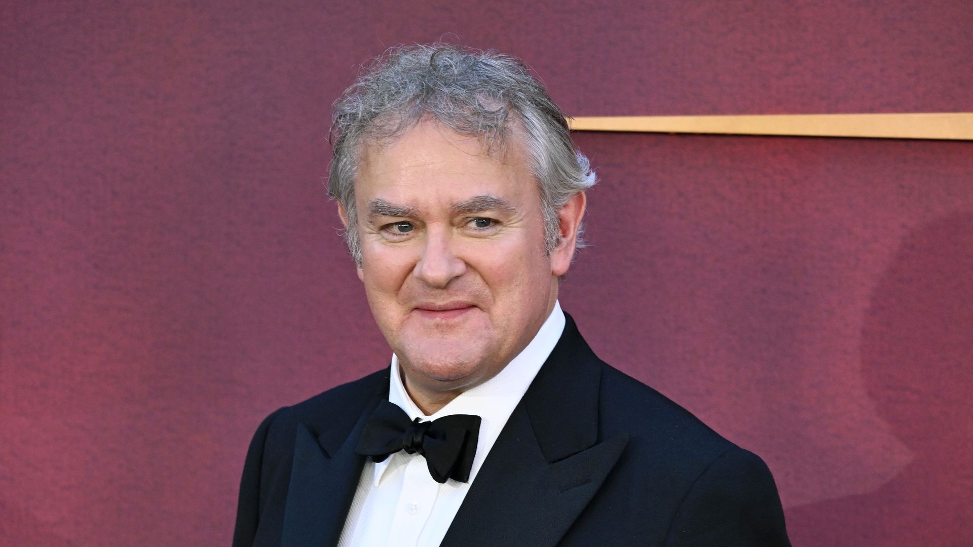 Hugh Bonneville at the premiere of "Downton Abbey: The Grand Finale" world premiere. He is wearing a black tuxedo and a white shirt. 
