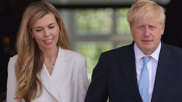 Boris Johnson in a blue suit and his wife Carrie in a white suit