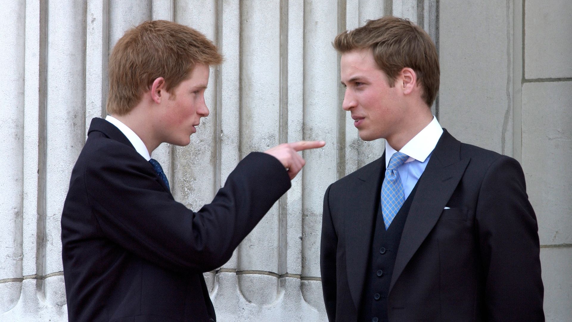 Prince Harry and Prince William in suits; Harry is pointing at William