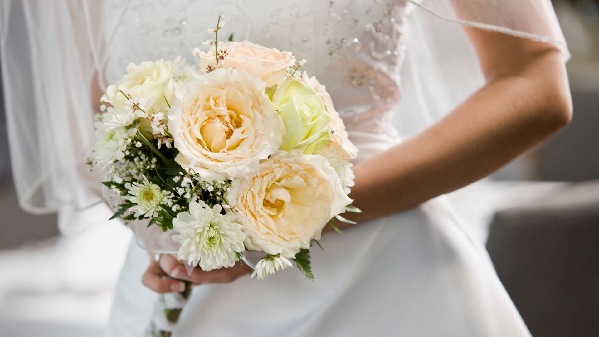 Bride holding bouquet, mid-section
